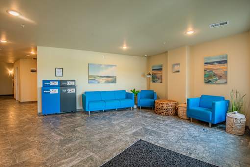 A waiting room with blue chairs and a grey floor.