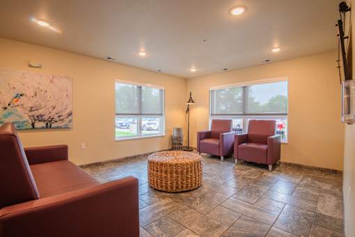 A living room with a large painting, two chairs, and a wicker ottoman.