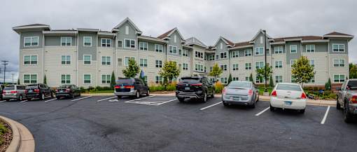 A parking lot in front of a large apartment building.