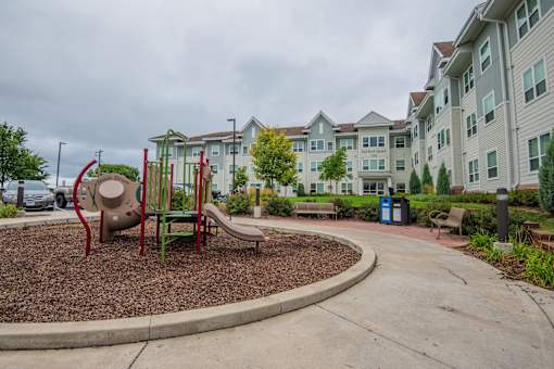 A playground with a slide and a red and green swing set.