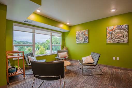 A room with green walls and a large window with a view of trees.