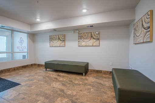 A room with a green couch and two paintings on the wall.
