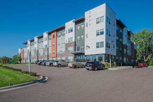 A multi-story apartment building with cars parked in front.