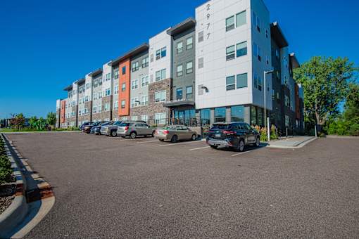 A parking lot in front of a multi-story apartment building.