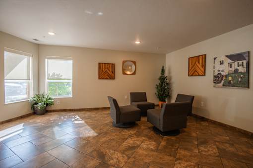 A living room with brown tiled floors and a small Christmas tree.