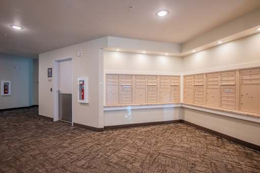 A hallway with a carpeted floor and a series of lockers on the wall.