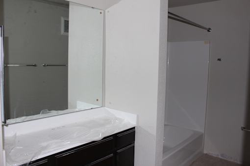 A bathroom with a sink, mirror, and shower.