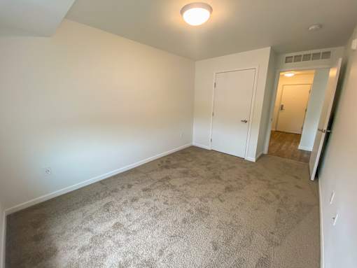 A carpeted room with a door and a light on the ceiling.