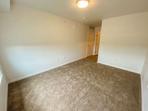A carpeted room with a doorway leading to another room.