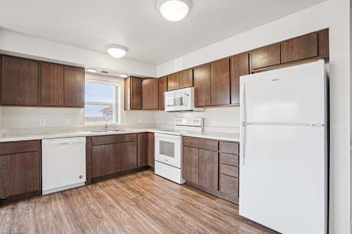 A kitchen with white appliances and brown cabinets.