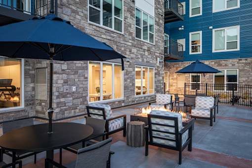A patio with a table and chairs and umbrellas.