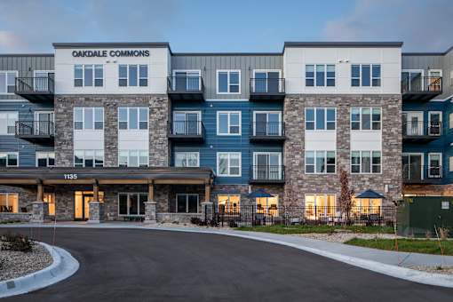 The image shows a multi-story residential building named Oakdale Commons with a driveway in front.