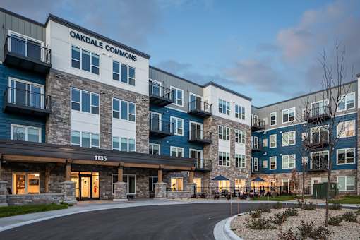The image shows the exterior of Oakdale Commons apartment building at dusk.