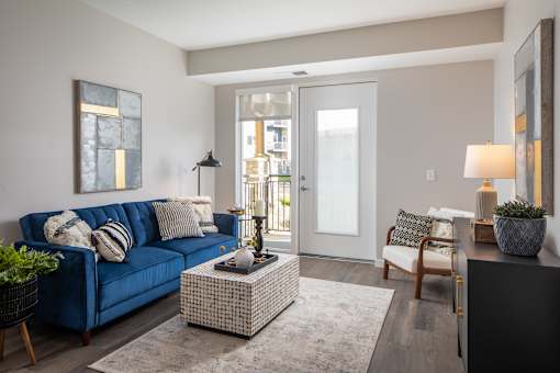A living room with a blue couch and a grey rug.