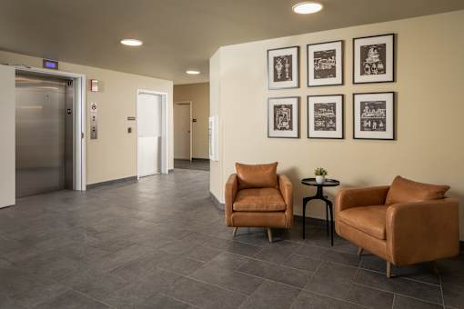 A hallway with chairs and pictures on the wall.