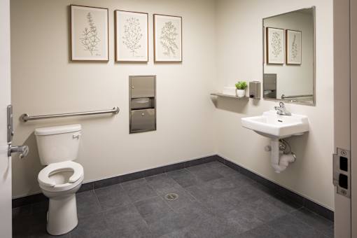 A bathroom with a toilet, sink, and mirror.