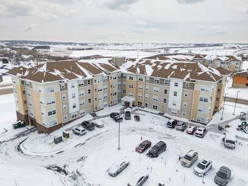 Apartment complex with cars parked in the snow.