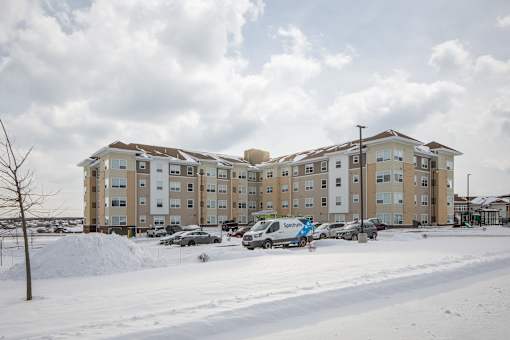 Apartment building with cars parked in front and snow on the ground.