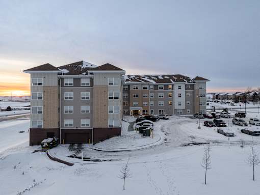 A large apartment complex with a parking lot in front.