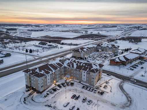 A large apartment complex is surrounded by a parking lot and a road.