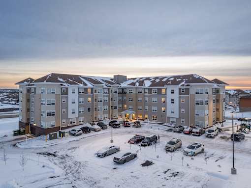 A large apartment complex with multiple buildings and cars parked in the lot.