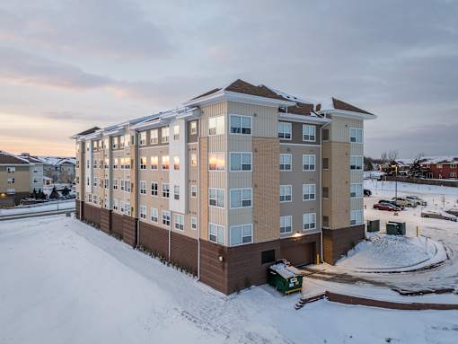 A large apartment building with a parking lot in front of it.