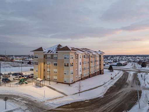 A large apartment building with a parking lot in front of it.
