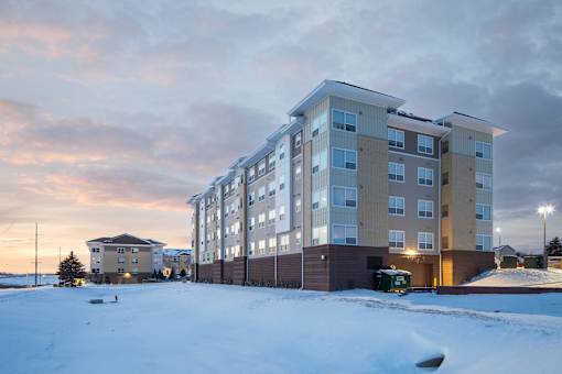 A large apartment building with a snowy ground in front.