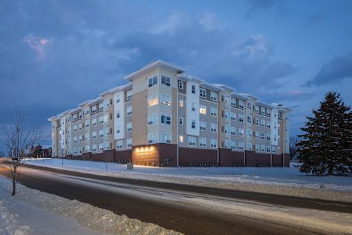 A large apartment building with a parking lot in front of it.