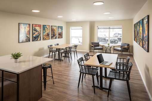 A room with a white counter and black chairs.