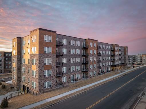 A large apartment building with a parking lot in front.