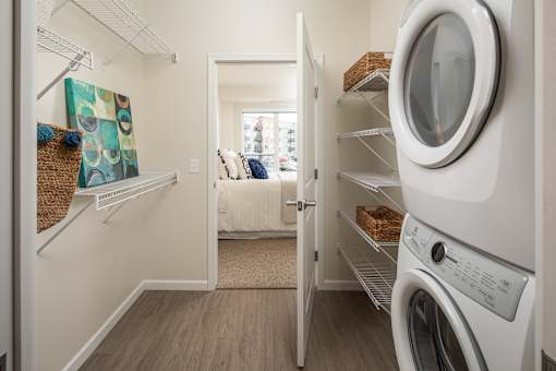A white washing machine is in a laundry room with a door open.