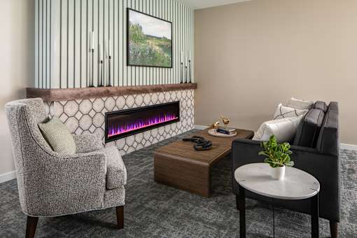 A grey chair is in front of a fireplace in a room.