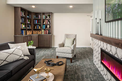 A living room with a black couch, a chair, a coffee table, and a bookshelf.