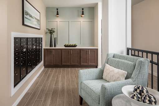A grey armchair with a pillow is in front of a cabinet with glass doors.