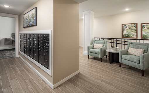 A room with a long black cabinet and two green chairs.