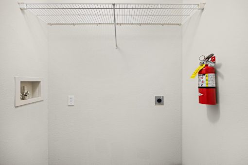 A red fire extinguisher is mounted on a white wall.