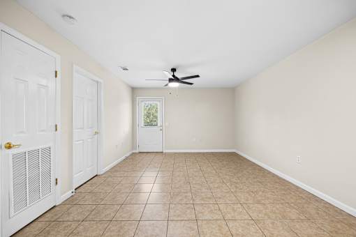 A room with a ceiling fan and tile flooring.