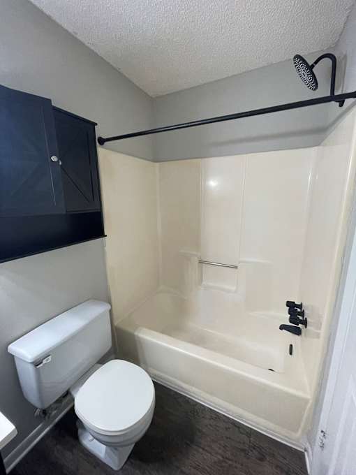 A white toilet sits next to a bathtub in a small bathroom.