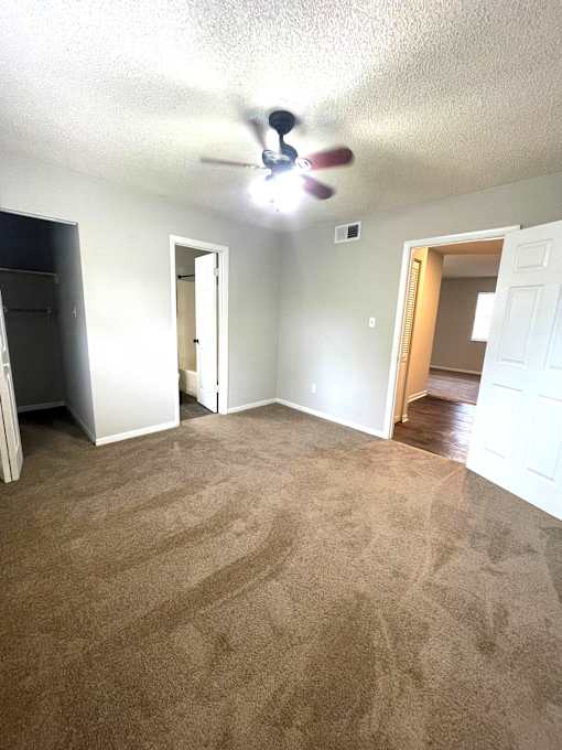 A room with a ceiling fan and carpeted floor.