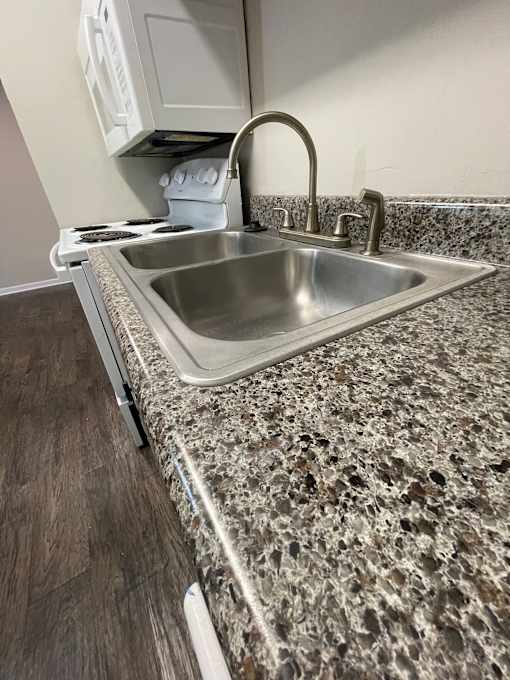 A kitchen with a granite countertop and a stainless steel sink.