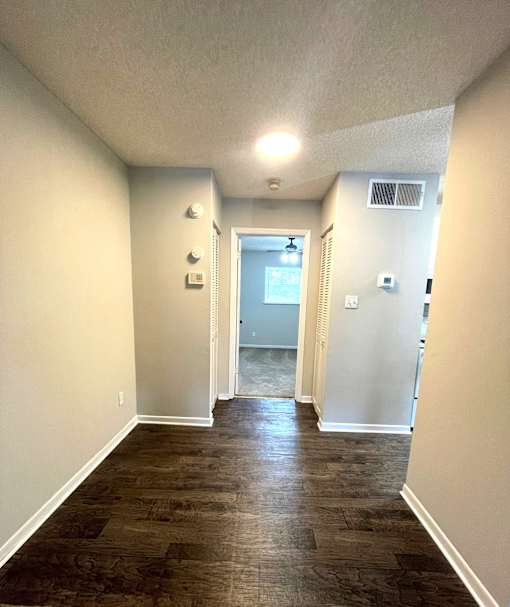 A long, narrow hallway with wood flooring and white walls.