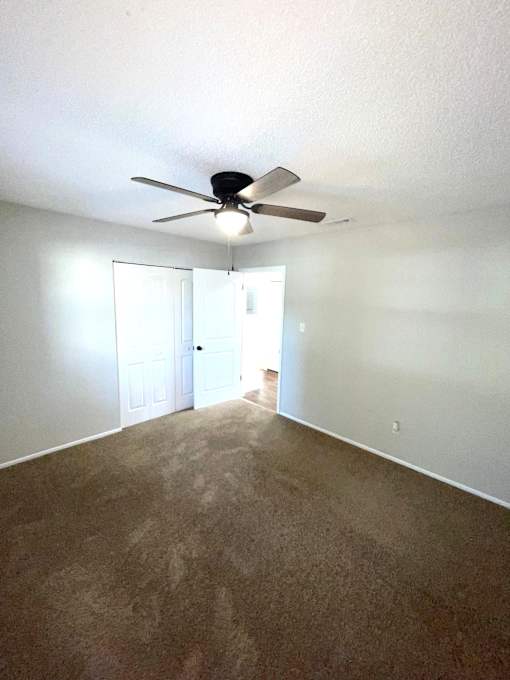 A room with a ceiling fan and carpeted floor.
