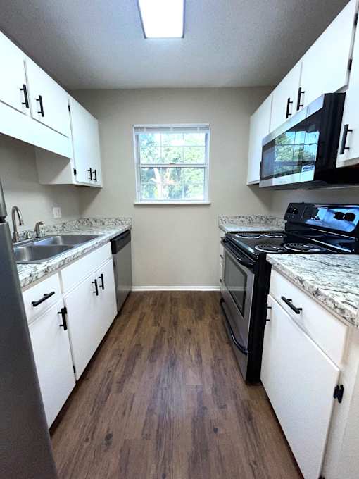 A kitchen with white cabinets and a window.