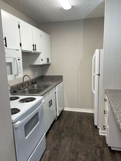 A kitchen with white appliances and cabinets.