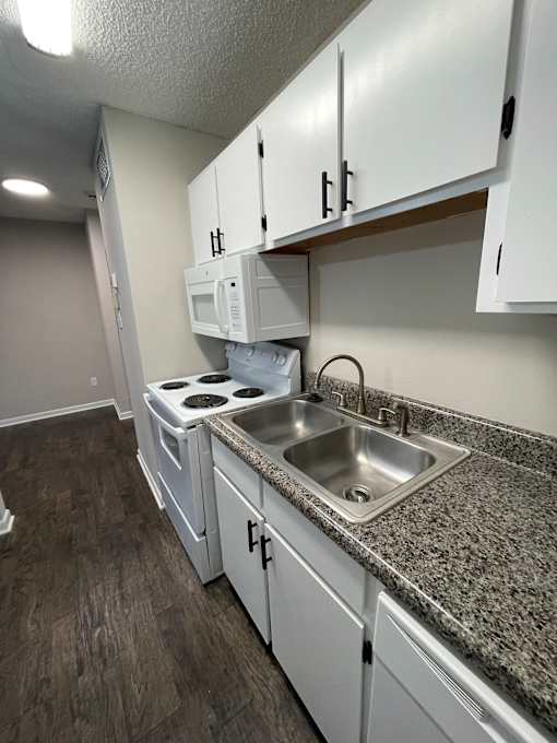 A kitchen with white cabinets and a granite countertop.