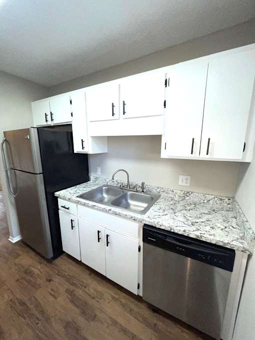 A kitchen with a granite counter top and stainless steel appliances.