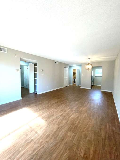 A room with wooden flooring and a chandelier hanging from the ceiling.