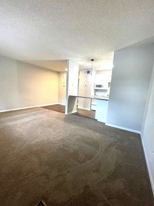 A carpeted room with a doorway leading to another room.