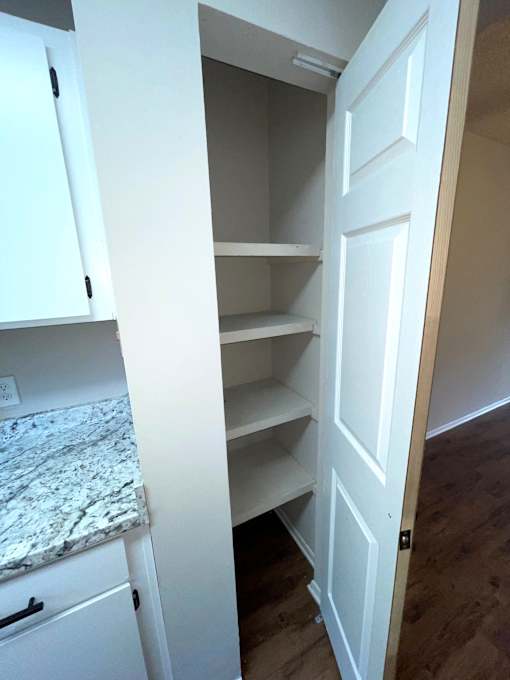 A white door is open to a room with a marble countertop.